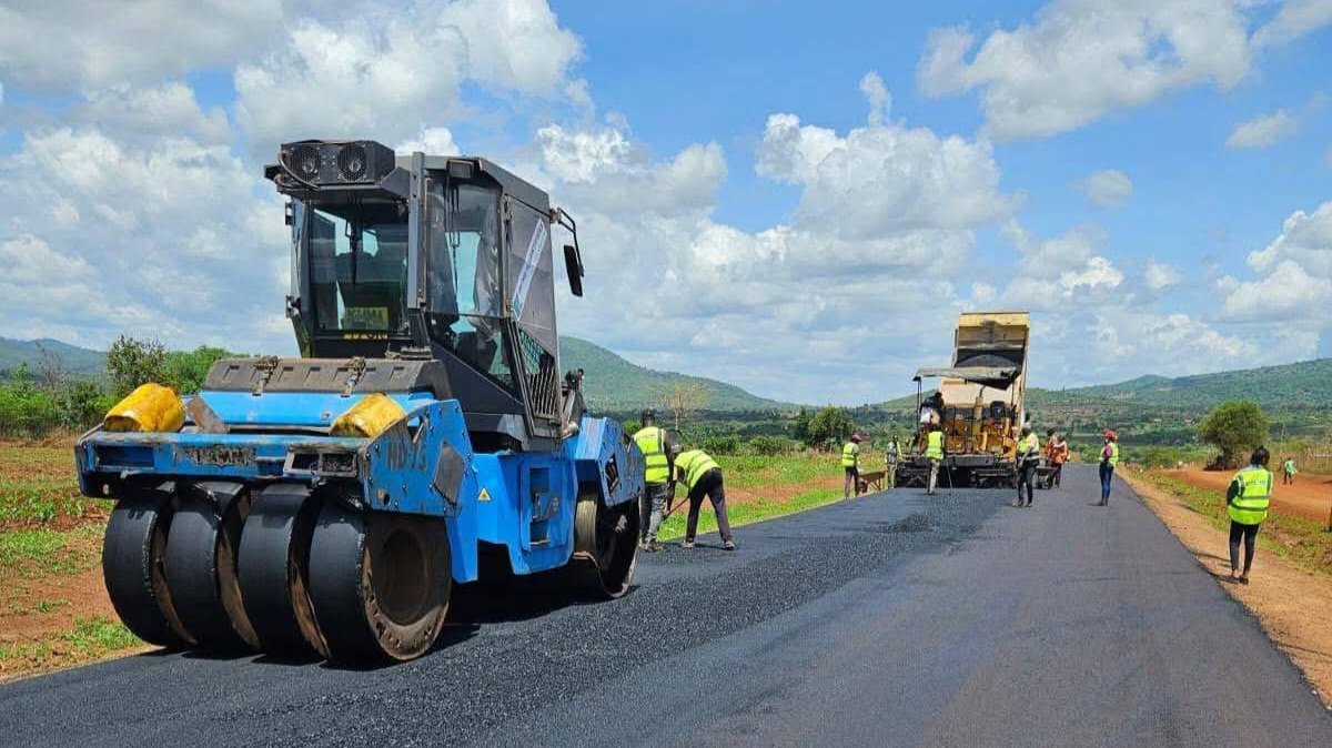 Heavy road construction machinery laying fresh asphalt on the Emali-Matiliku road section in Kenya during the upgrading project.