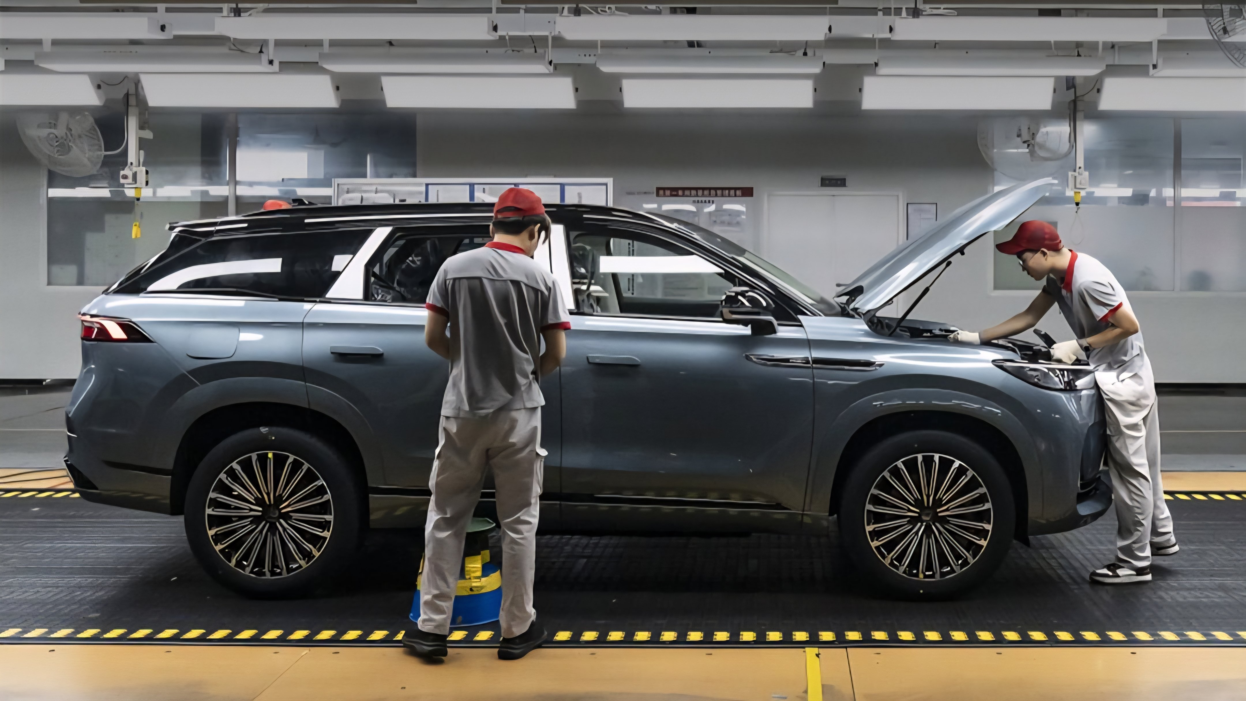Exterior view of an automotive manufacturing plant as referenced in 262591.png, showing workers inspecting a vehicle on an assembly line.