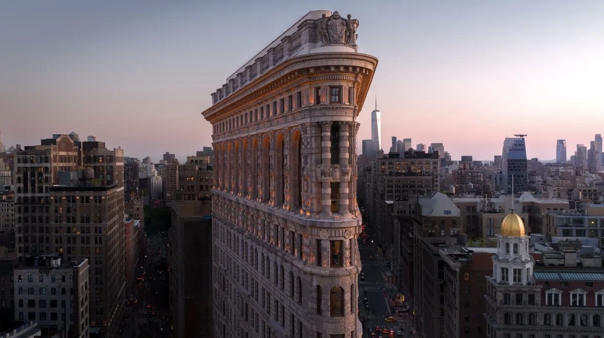 Exterior view of the Flatiron Building illuminated at night during ongoing restoration work in New York City