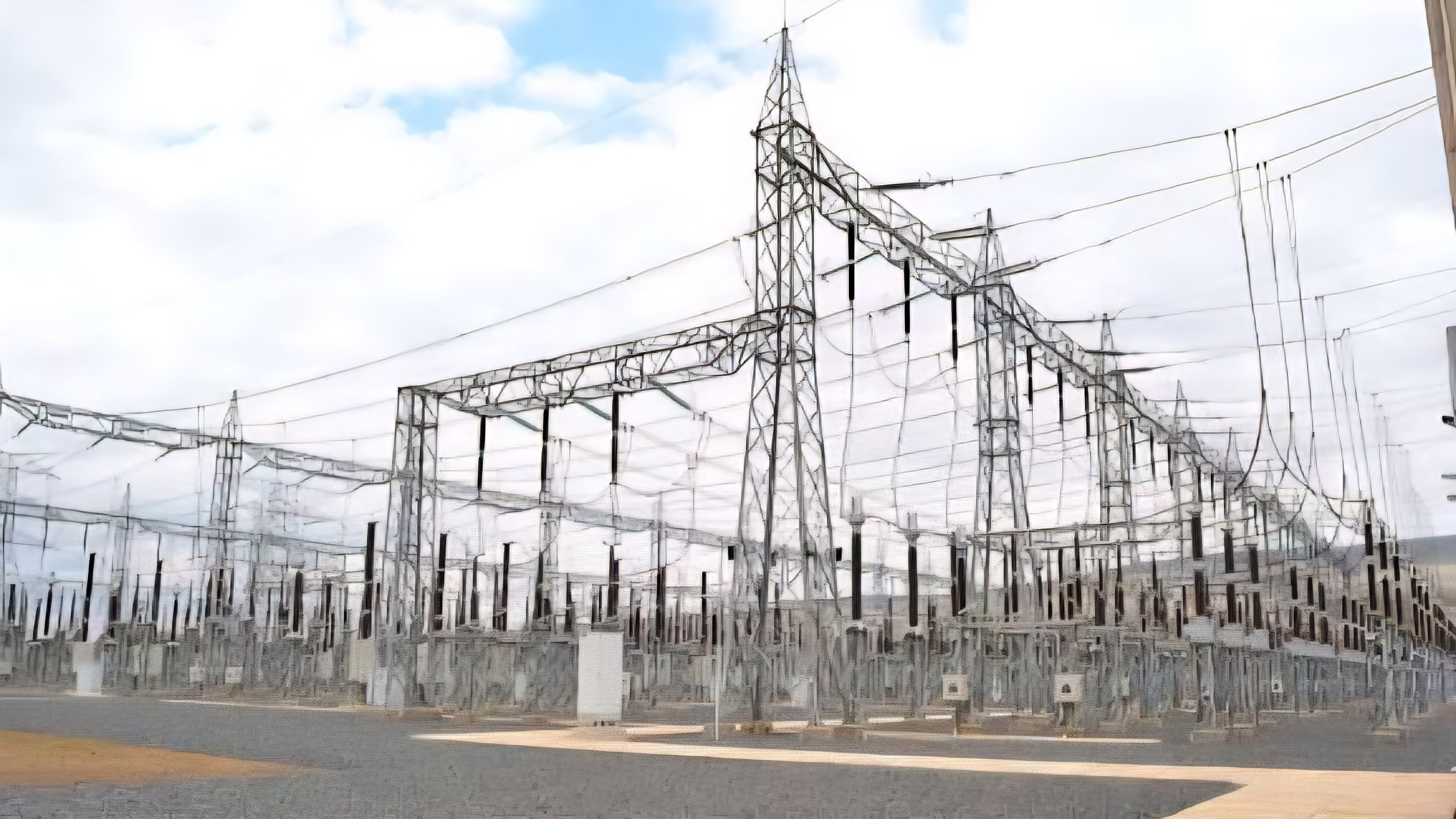 A high-voltage electrical substation with large transformers, steel pylons, and circuit breakers under a clear sky.