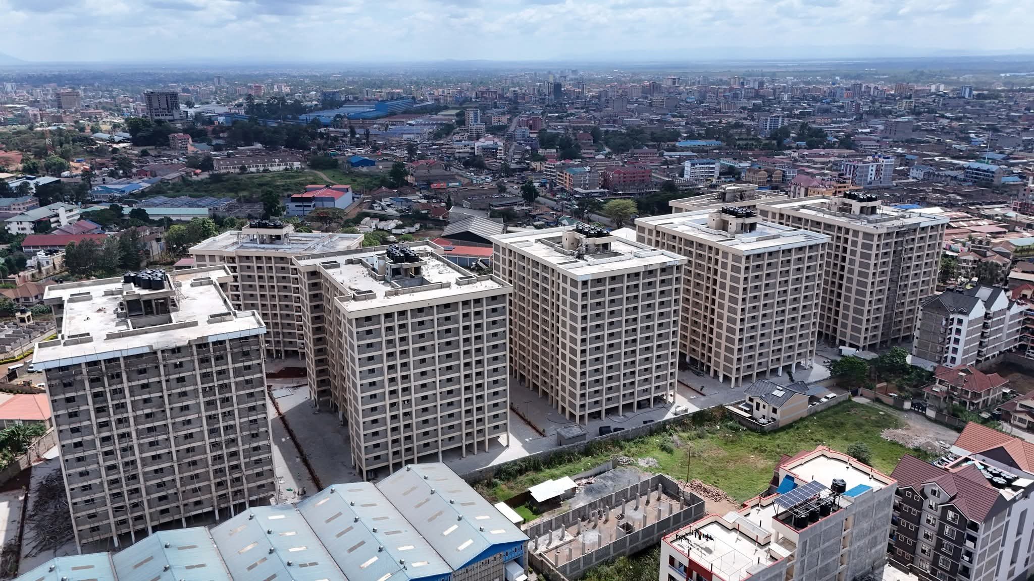 Aerial view of several multi-storey residential blocks at the Kings Boma Estate in Ruiru, showing completed exterior painting and furnished interiors..