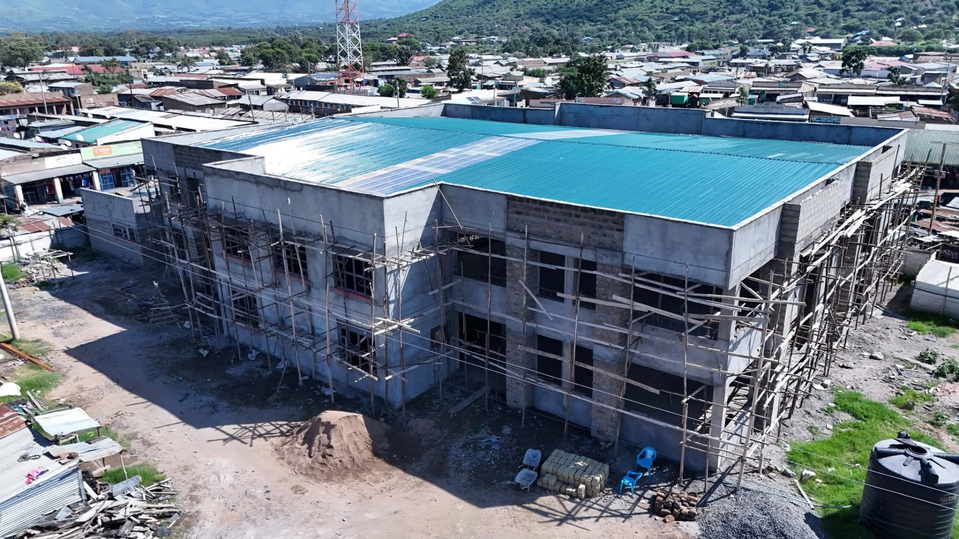 Exterior view of the nearly complete two-storey Sindo ESP Market building in Homa Bay County, Kenya, showing ongoing plastering work.