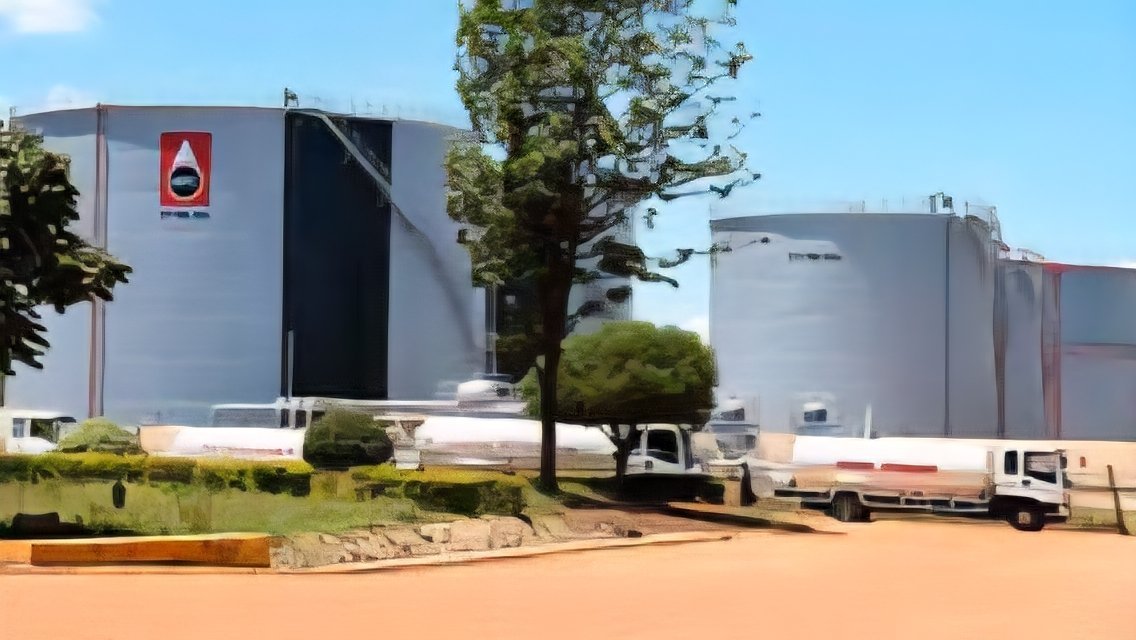 An aerial view of large white oil storage tanks at a Kenya Pipeline Company depot with fuel tanker trucks lined up at the loading bay.