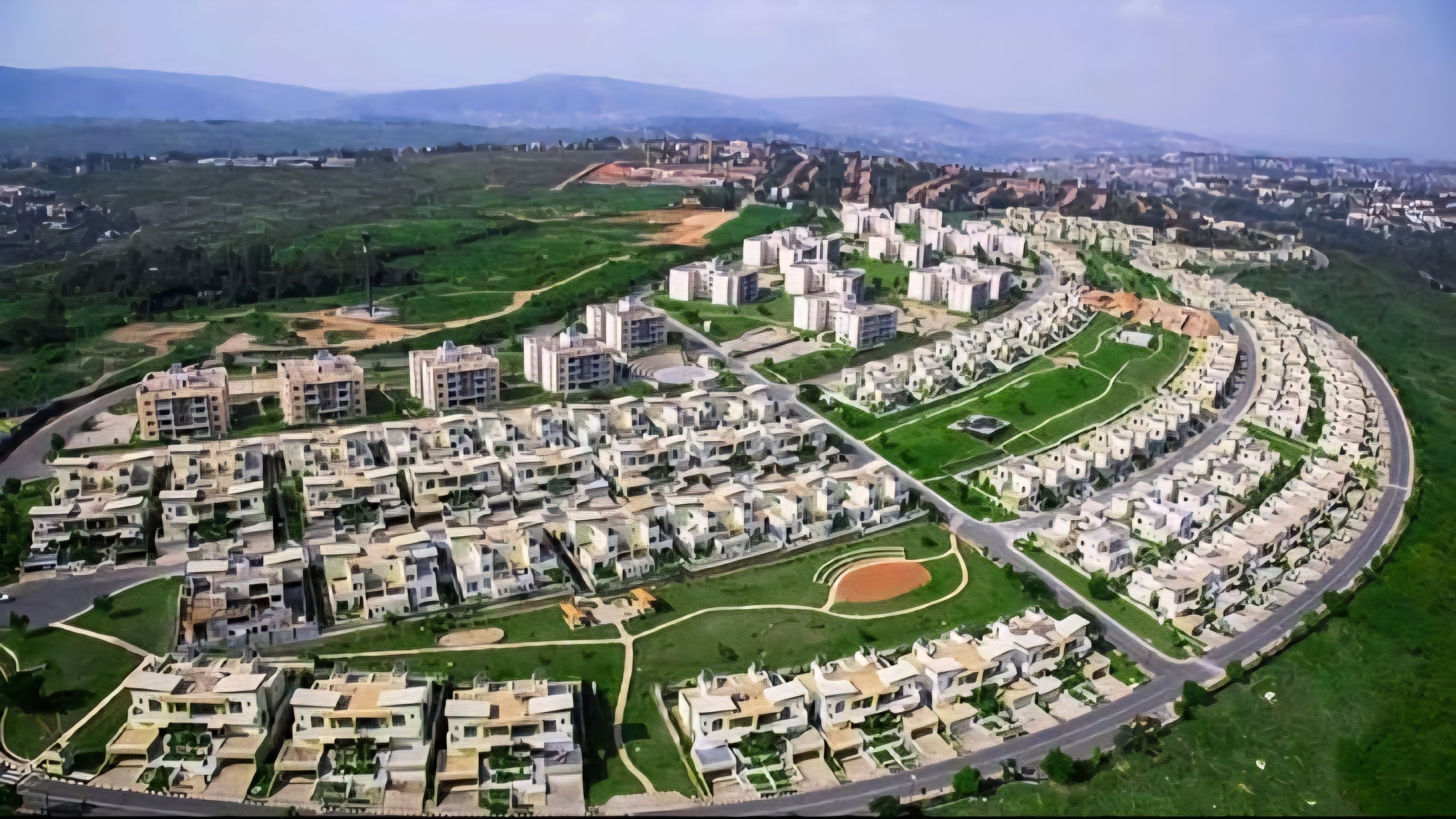 Aerial view of a modern residential estate development featuring multi-storey housing units and paved road infrastructure.