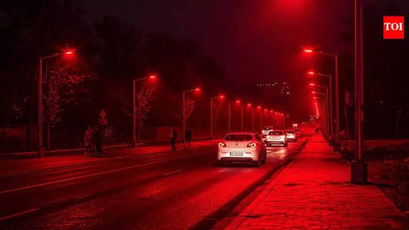 A row of streetlights emitting a deep red glow along a paved Danish roadway at night.
