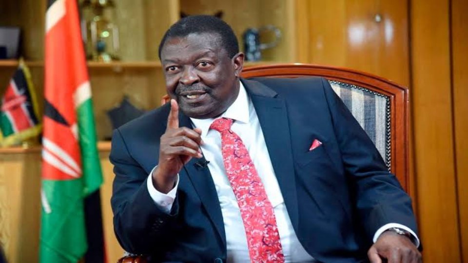 Close-up of Prime Cabinet Secretary Musalia Mudavadi speaking at a podium with the Kenyan flag in the background.