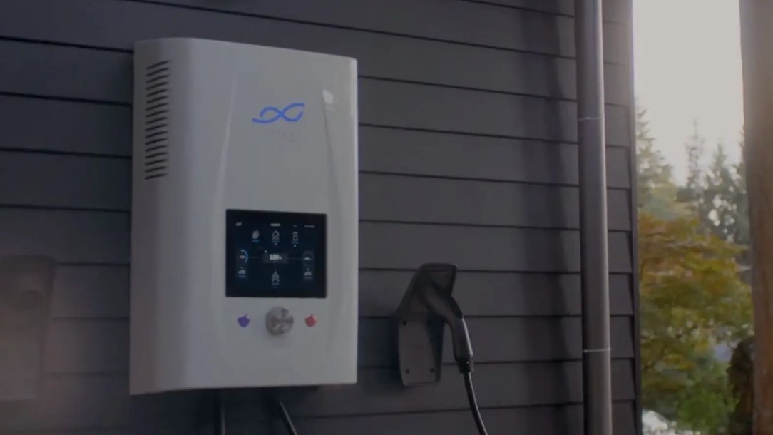 Wall-mounted residential battery storage system connected to a home solar charger on an exterior house wall.
