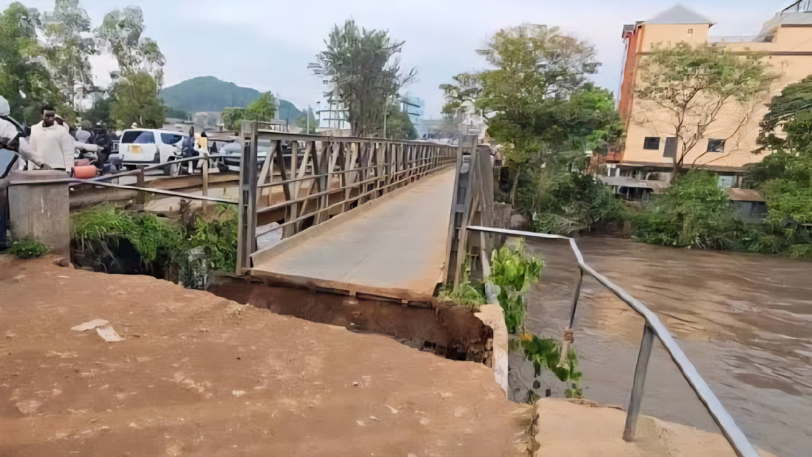 A bridge in Migori with a severely eroded approach road and visible structural damage next to a flowing river.