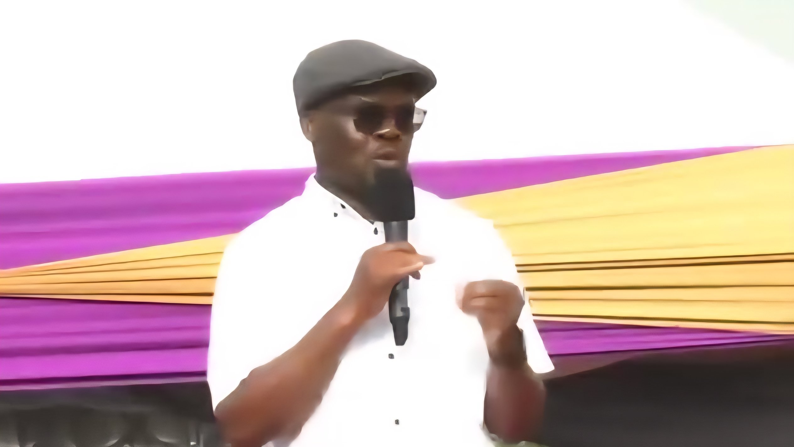 A high-angle view of a government official speaking into a microphone at a podium during an outdoor infrastructure commissioning event in Kenya.