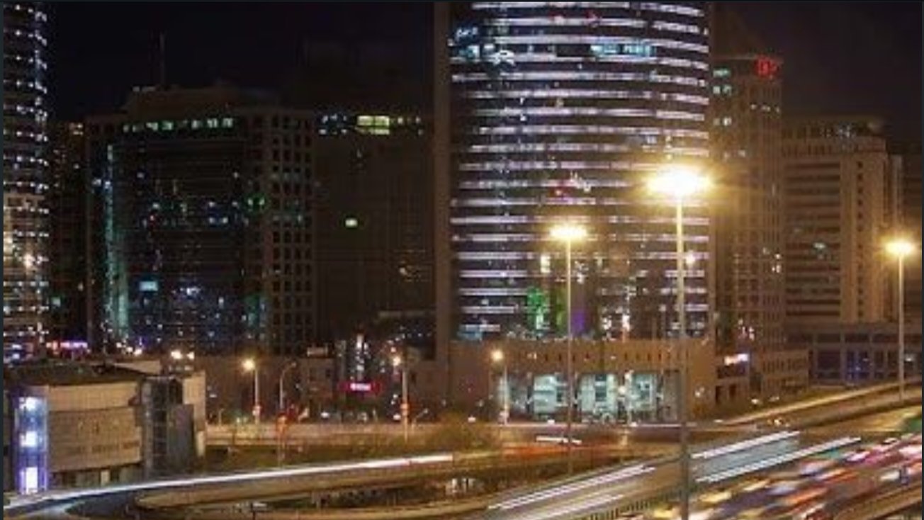 A smartphone screenshot of a social media post displaying an urban highway interchange at night with text overlay regarding China's desert solar project.