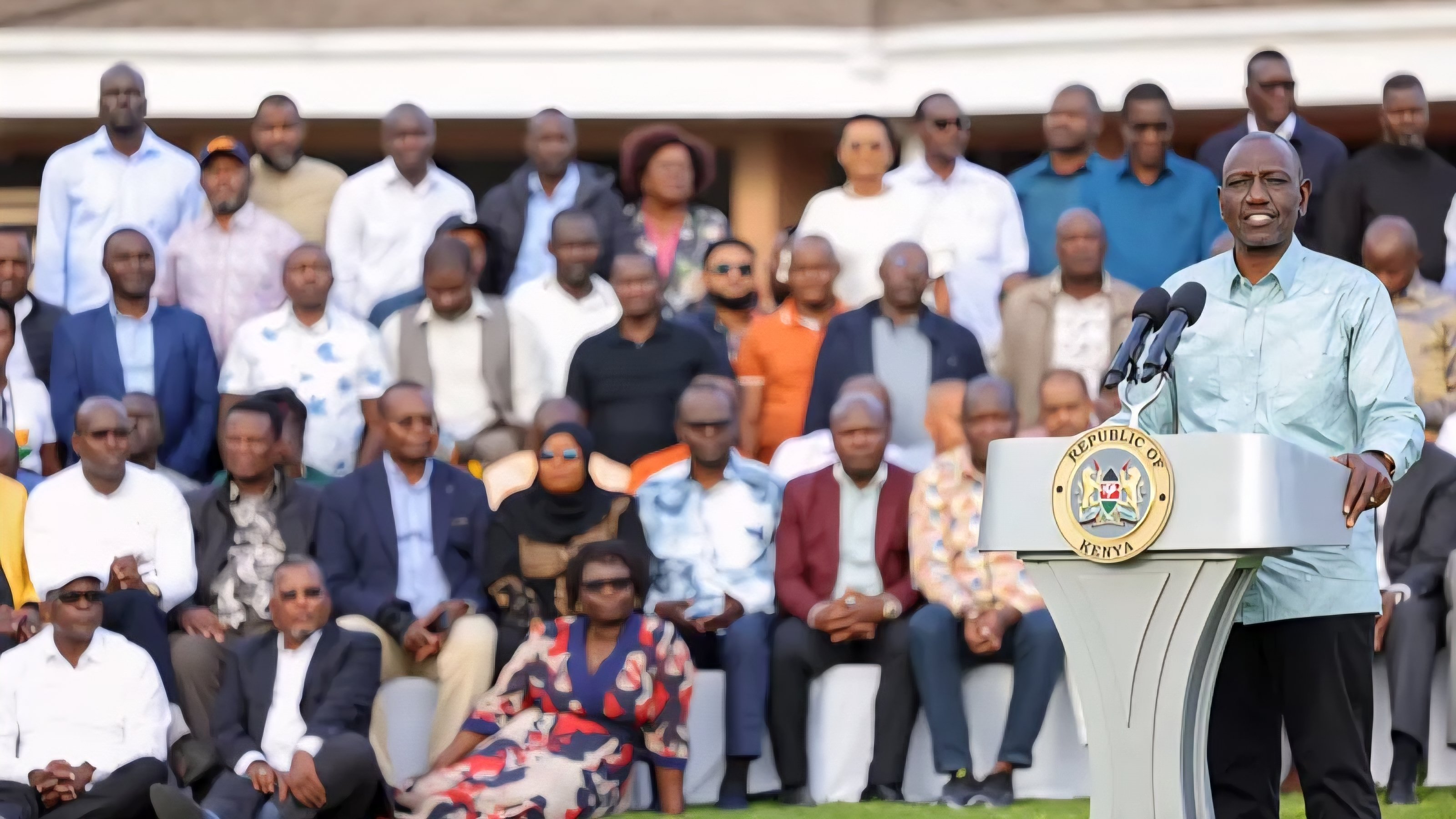 President William Ruto addressing an audience at an outdoor event surrounded by government officials.