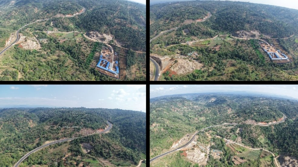 Deep valley with an existing bridge structure and surrounding hilly terrain under construction activity