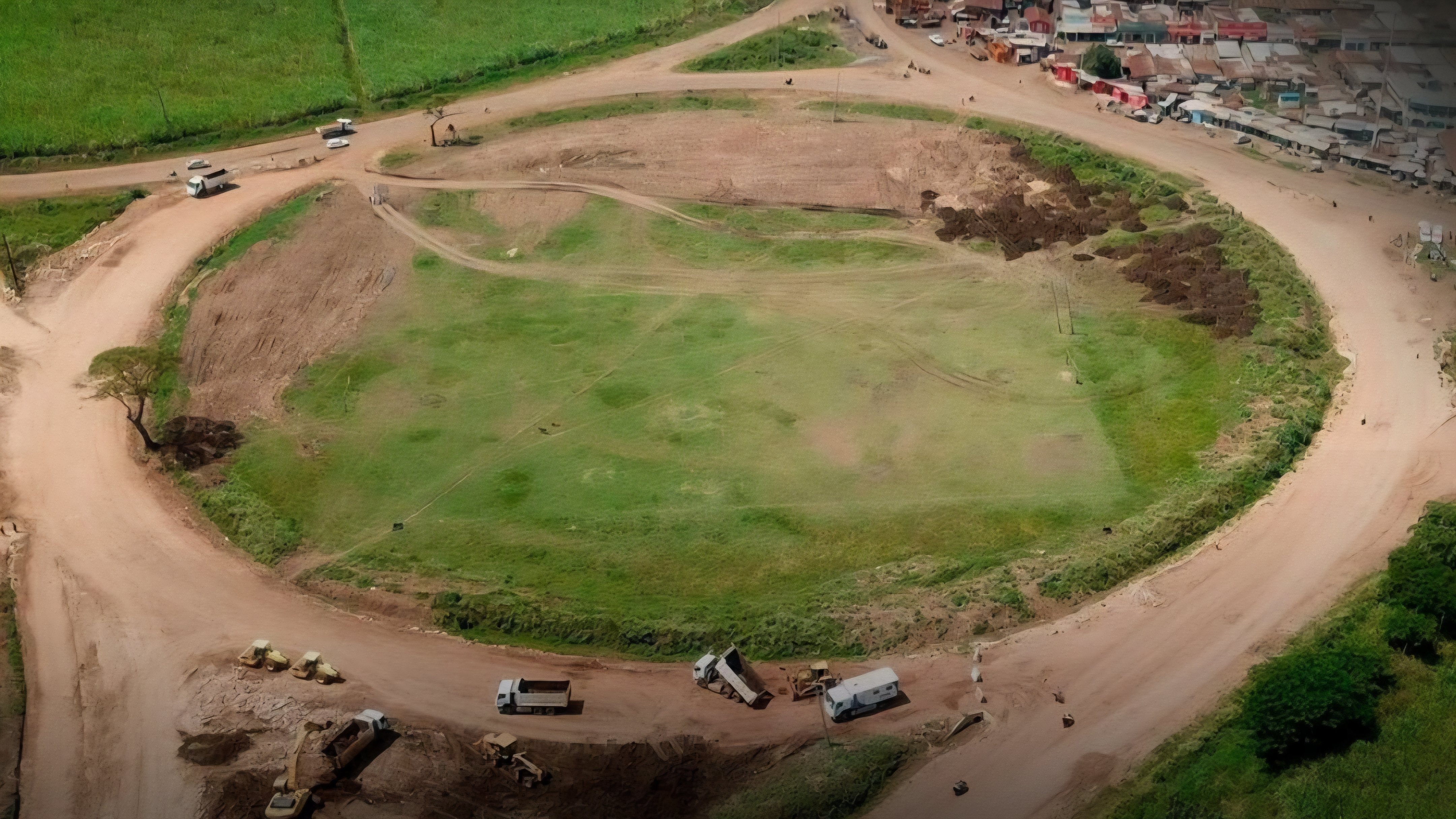 Heavy construction machinery, including a road roller and an asphalt paver, working on a section of the Mamboleo-Miwani-Chemelil-Muhoroni road in Kisumu County.