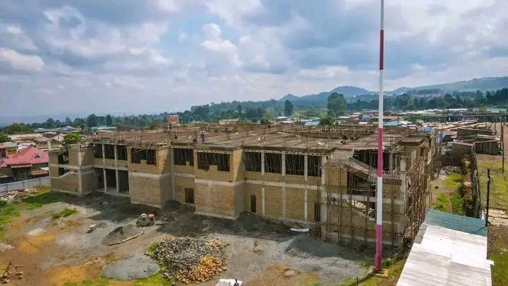 Elevated perspective of the New Bahati Centre Mega Market building under construction, showing reinforced concrete columns, suspended slabs, and stone masonry walls in Nakuru County.