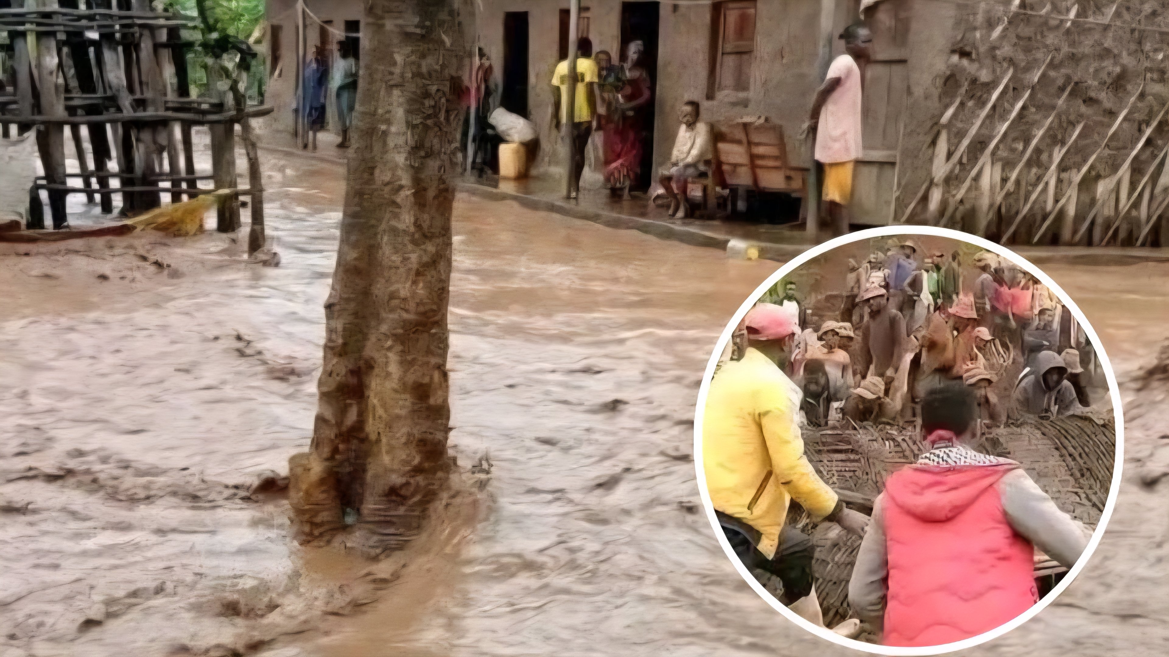 A muddy river flows rapidly past damaged residential buildings and trees in a flooded area of Ethiopia.