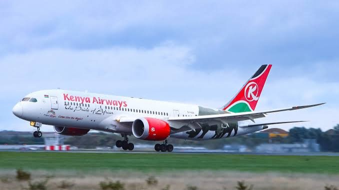 A Kenya Airways Boeing 787 Dreamliner taxiing on the runway at Jomo Kenyatta International Airport during sunset.
