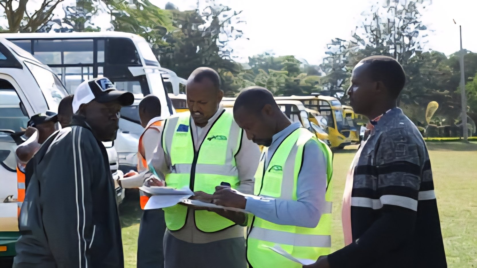 National Transport and Safety Authority officers in high-visibility vests inspect compliance documents alongside public service vehicles on a grassy field in Kenya.