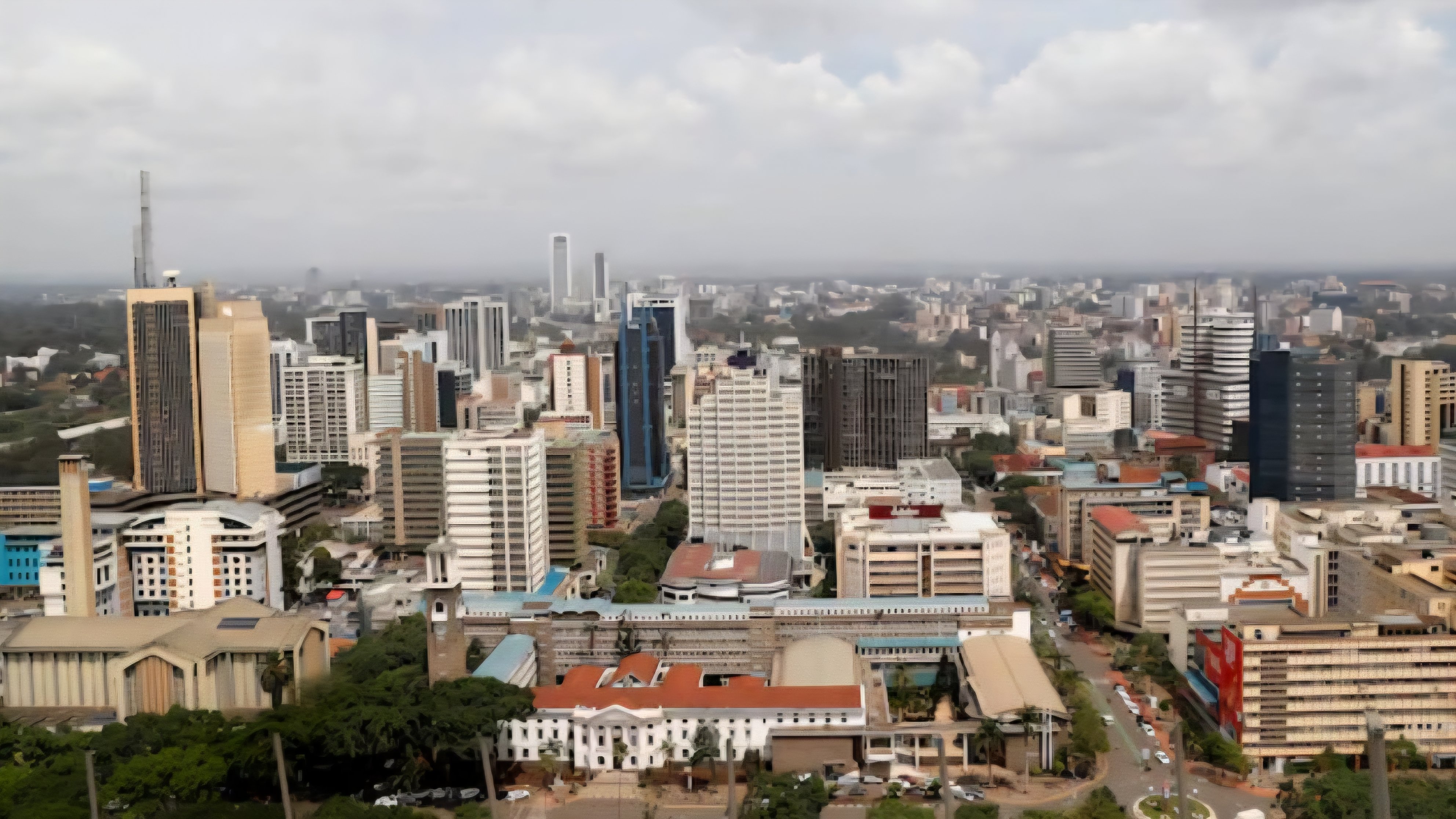 A wide, elevated view of downtown Nairobi showing the high-rise commercial buildings and streets of the central business district under a daytime sky.