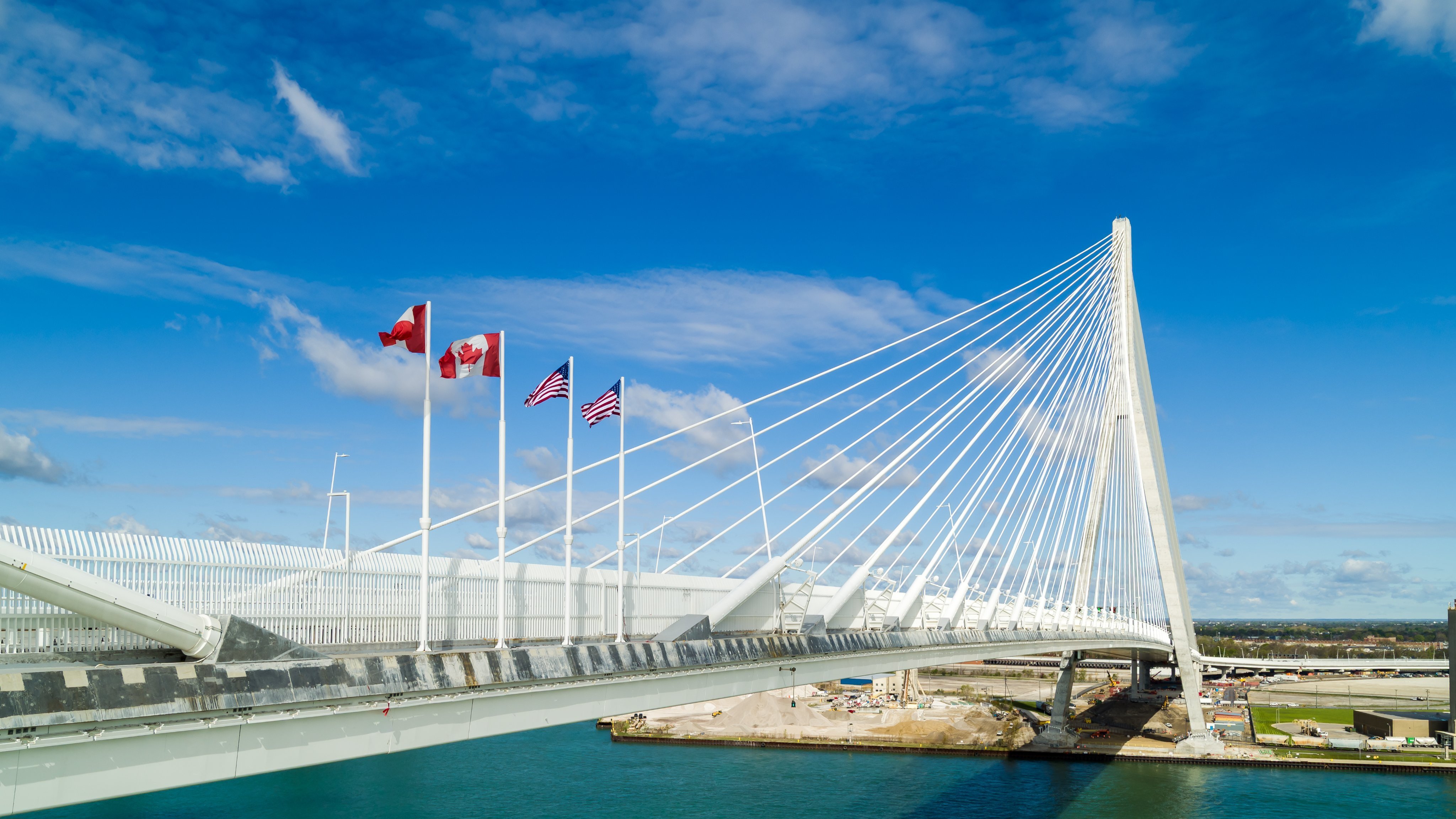 Canadian and American flags flying on the cable-stayed Gordie Howe International Bridge.