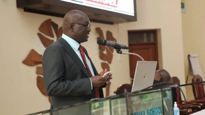 Public Service Commission official speaking at a podium during a news briefing at the Kenya School of Government.