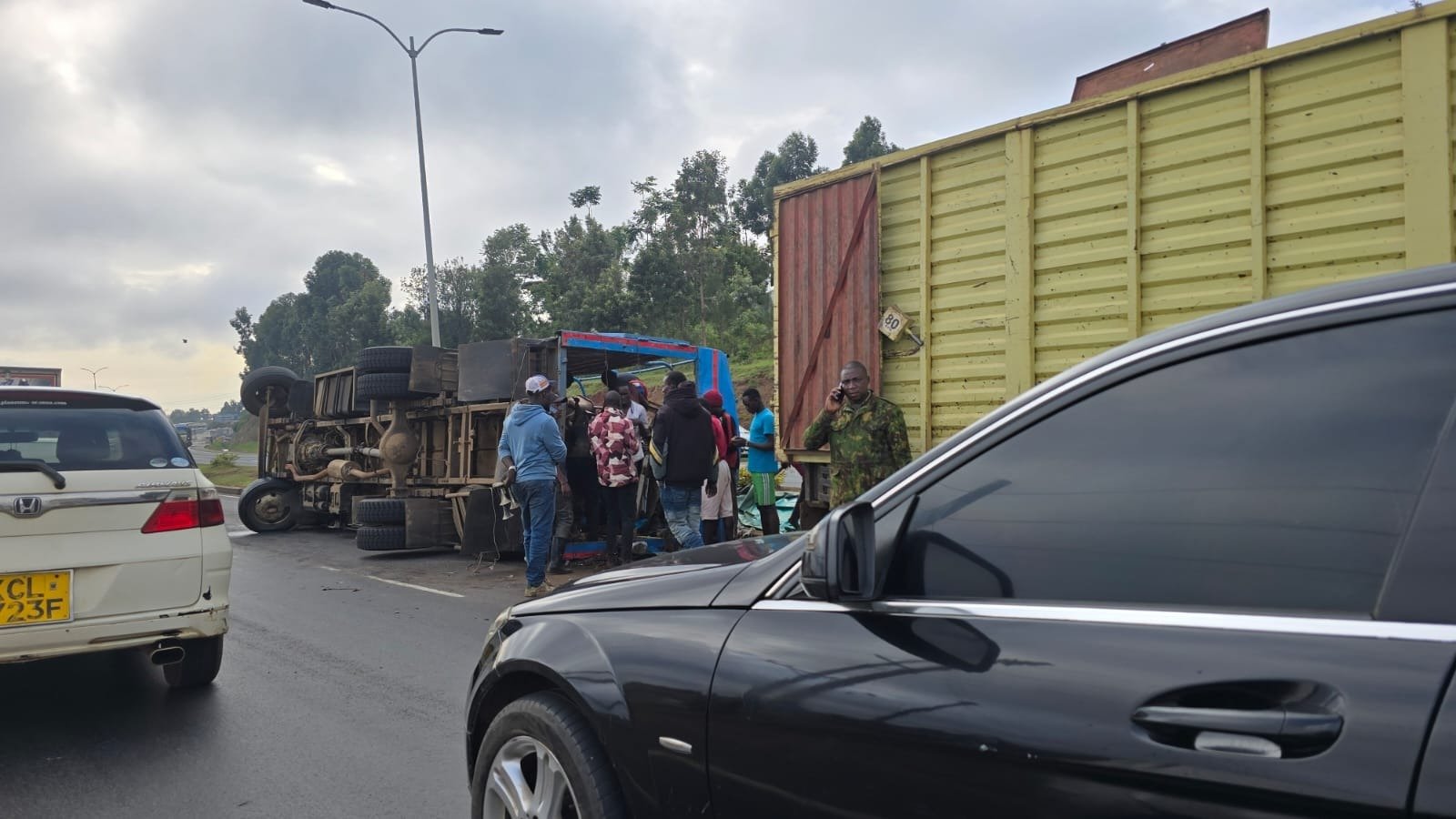 A large yellow commercial truck and other vehicles stopped on the Southern Bypass in Kenya following a road accident, with people gathered near the scene.