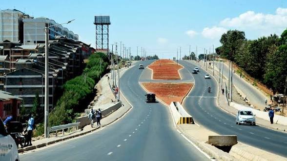 A wide-angle shot of the Southern Bypass in Lang'ata, Nairobi, showing a paved multi-lane highway with residential apartment buildings situated along the left side.