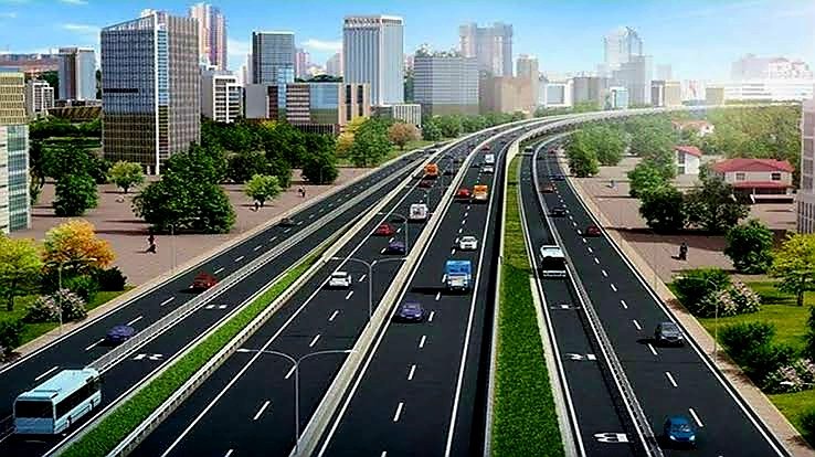 Wide shot of a multi-lane elevated highway showing traffic flow against a city skyline.