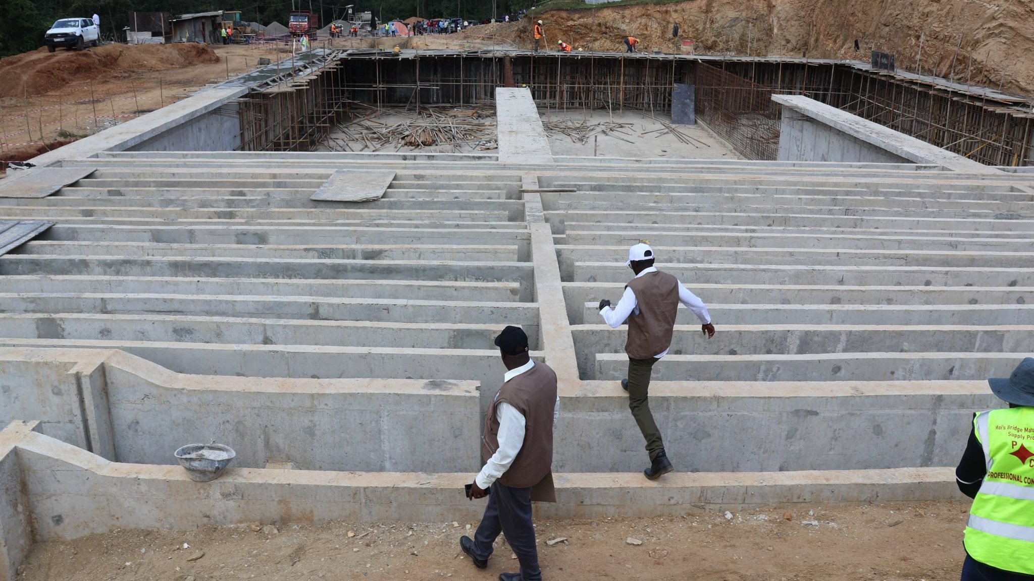 Cabinet Secretary Eric Mugaa and CEO Edwin Rotich inspecting construction works at a water infrastructure project site.