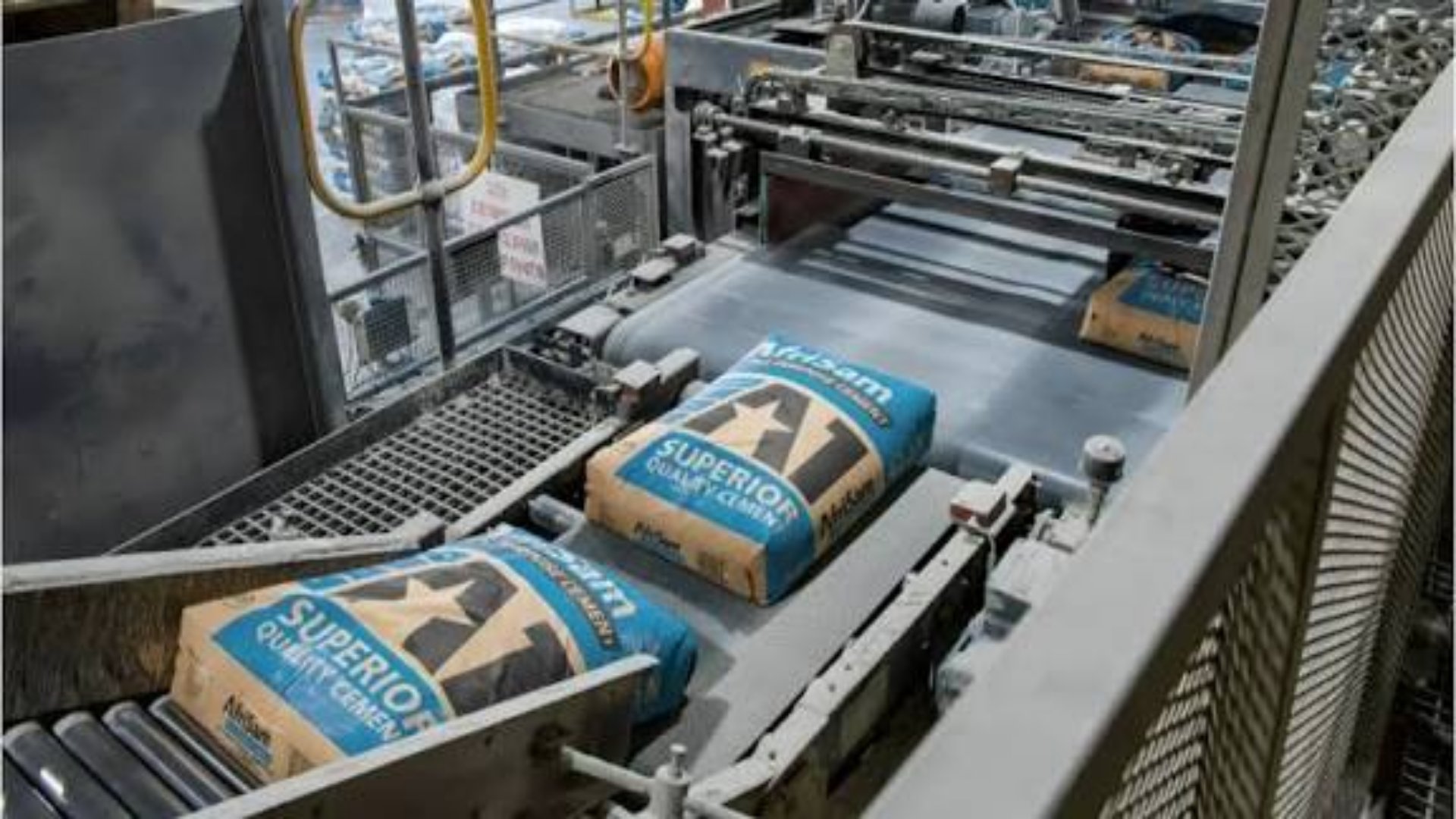 Industrial cement manufacturing facility with equipment running for cement production and packaging.