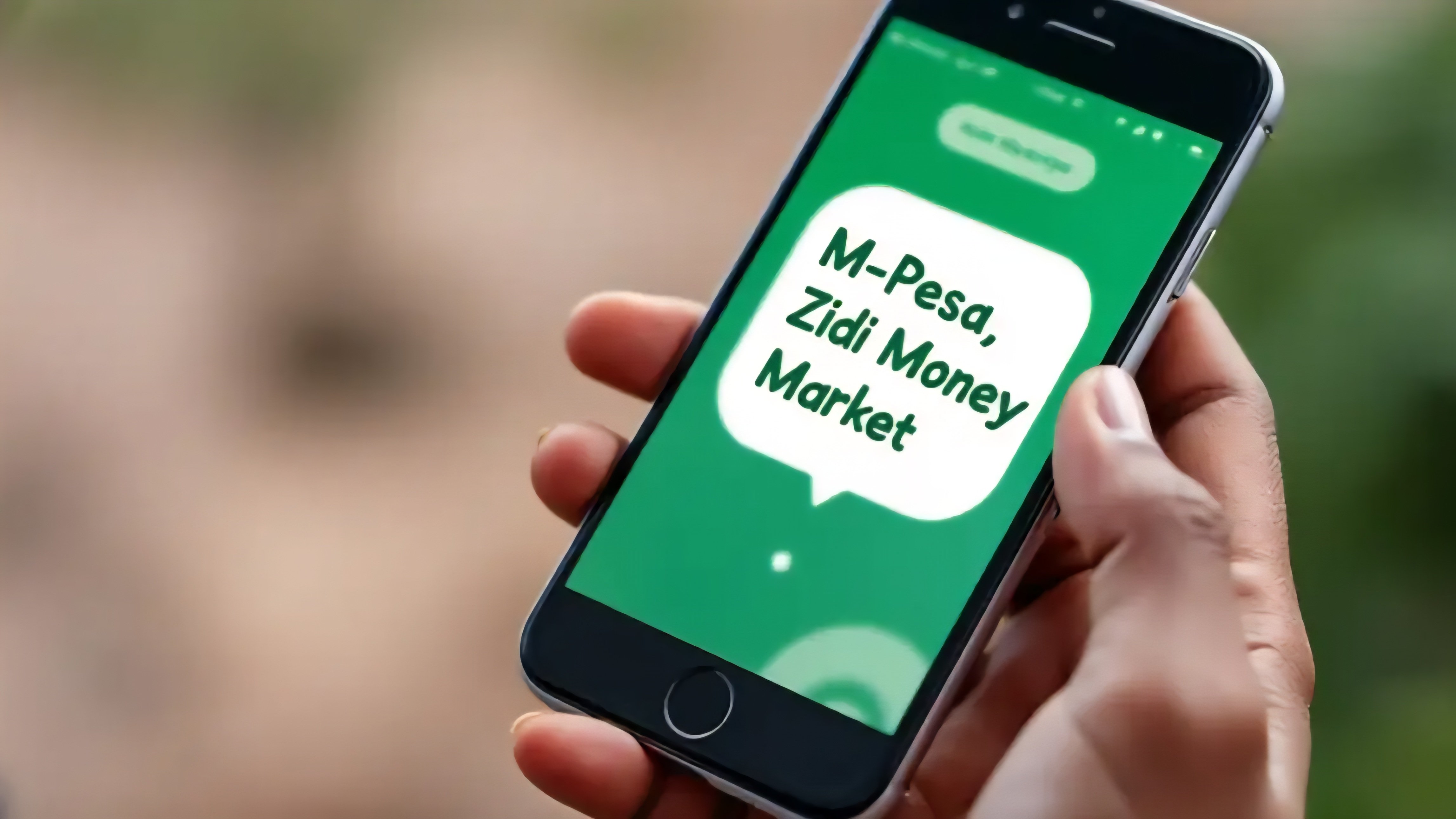 A close-up view of a smartphone screen displaying the M-PESA application interface with the Ziidi Trader investment menu selected, held against a blurred background of the Nairobi skyline.