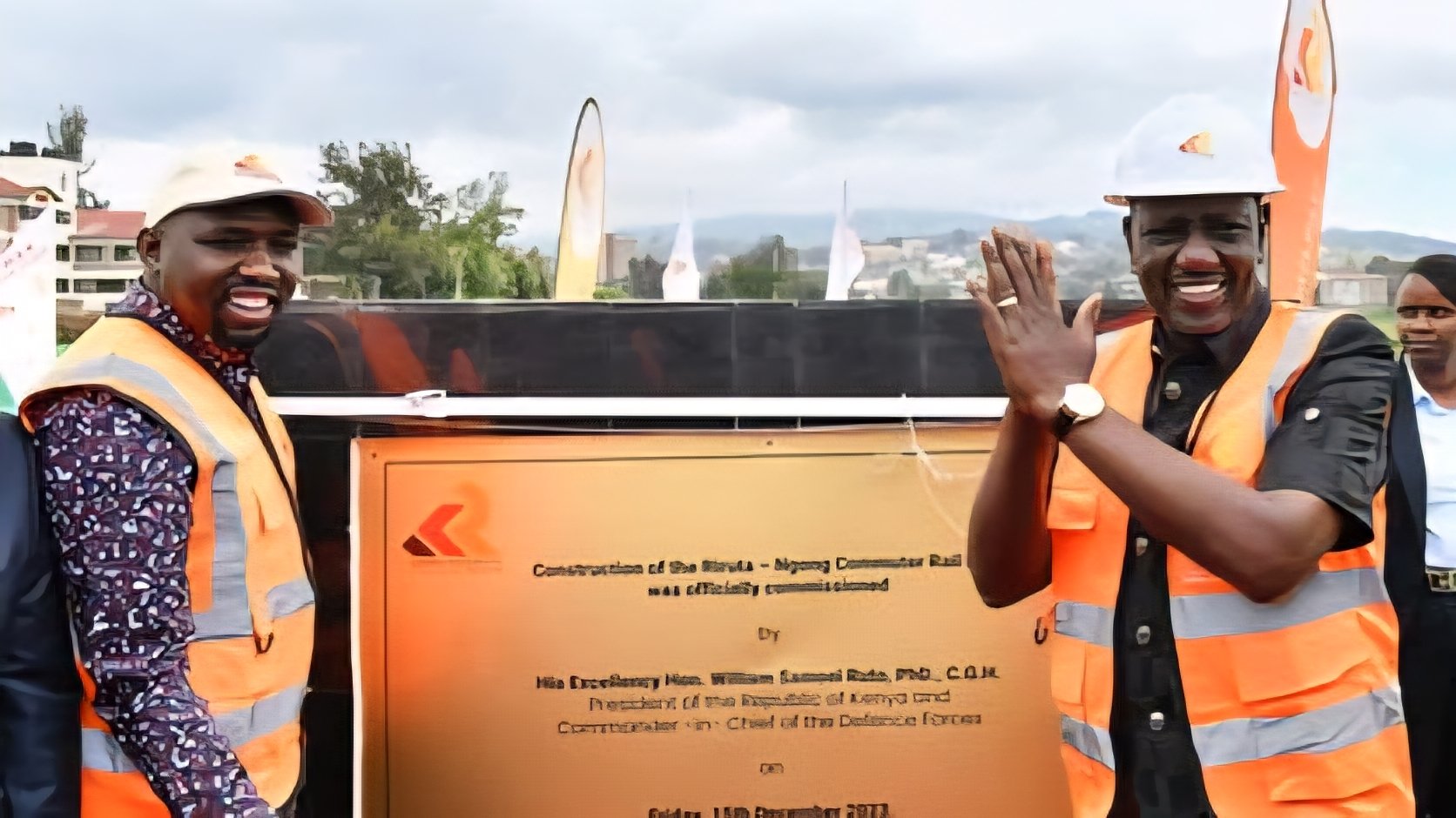 President William Ruto and government officials in high-visibility vests and hard hats standing before a commemorative plaque for the Riruta-Ngong Commuter Rail.