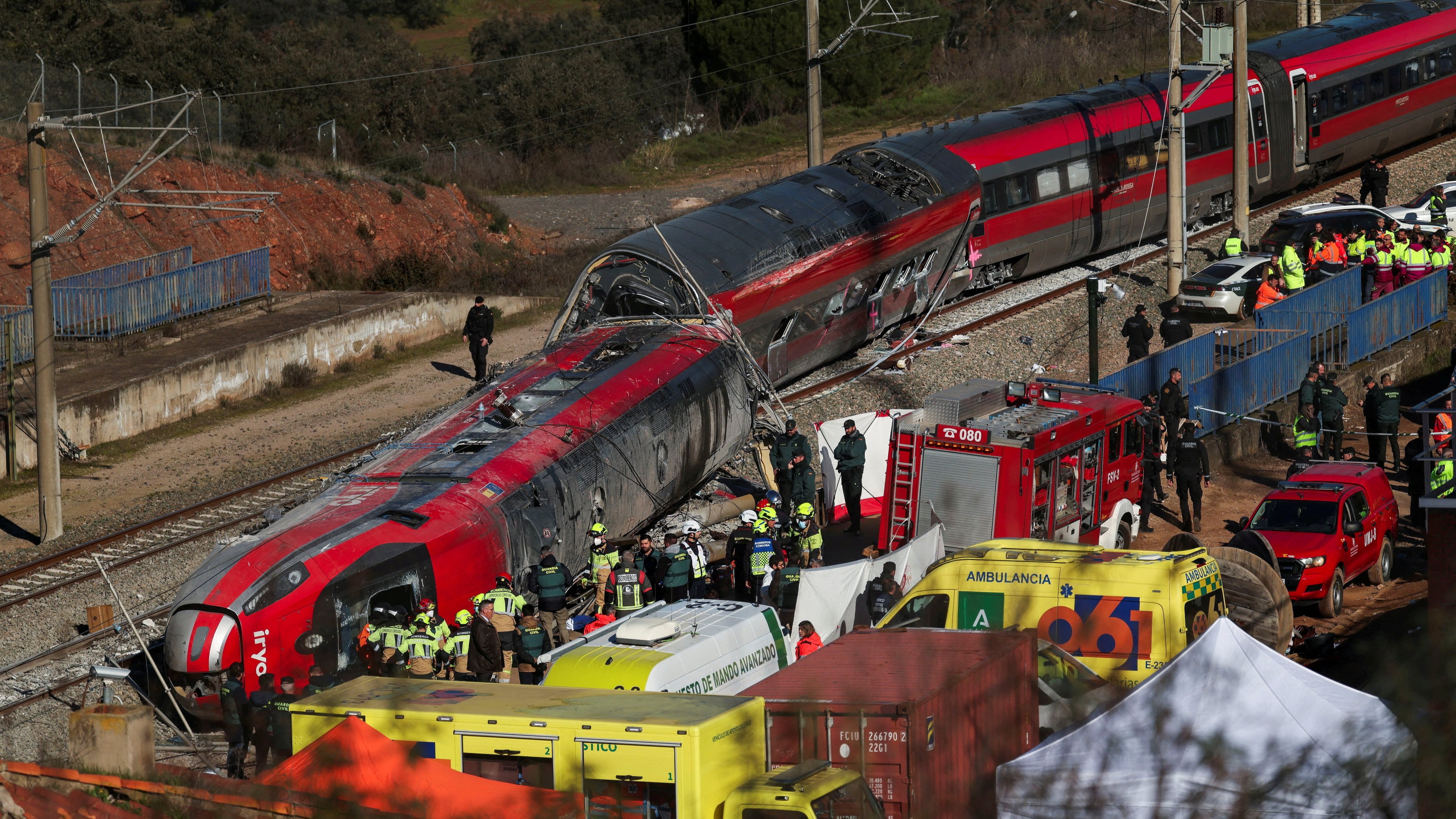 Wreckage of derailed high-speed trains after collision near Córdoba, Spain, with emergency responders and ambulances at the site.