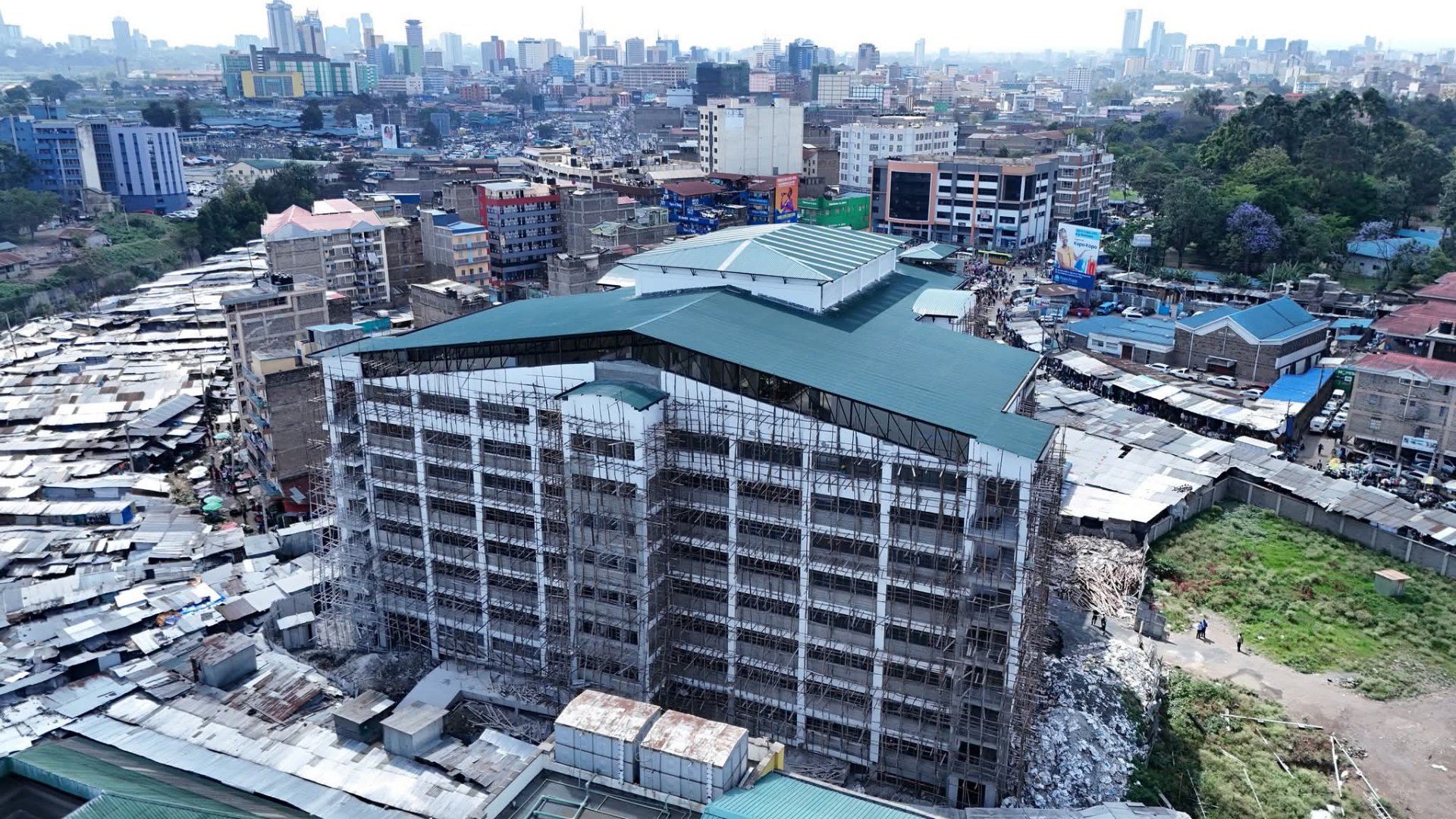 Views of the nearly completed, multi-storey Gikomba Quarry Road Market Block D building with construction workers visible on the lower floors.