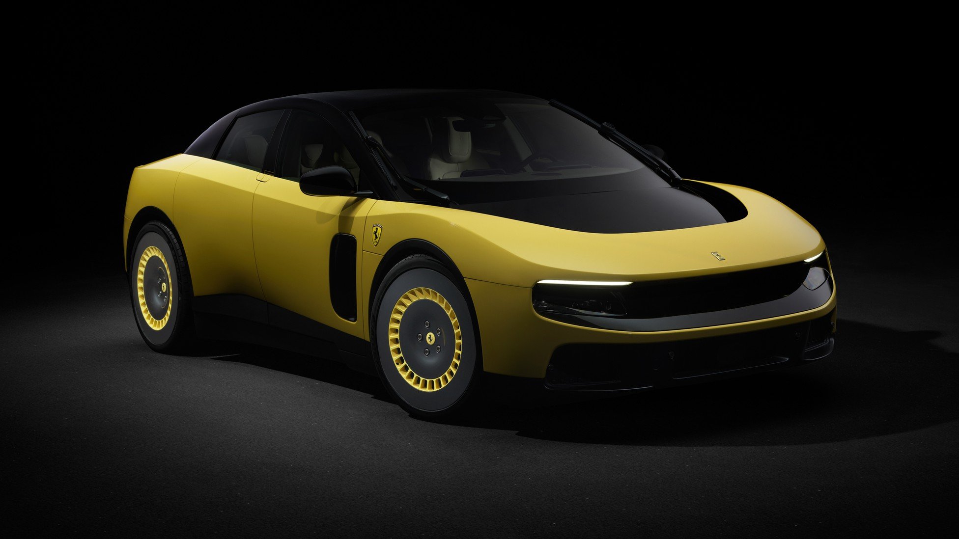 A sleek, yellow four-door Ferrari sports car with a curved black roofline, black hood, and distinctive retro-styled yellow disc wheels, displayed against a dark studio background.