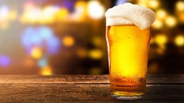 A close-up shot of a glass of beer on a wooden bar counter.