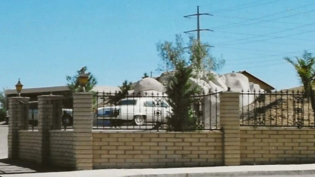 Exterior view of a street-level residential entrance structure and faux rock formations in Las Vegas, Nevada, concealing a subterranean house below.