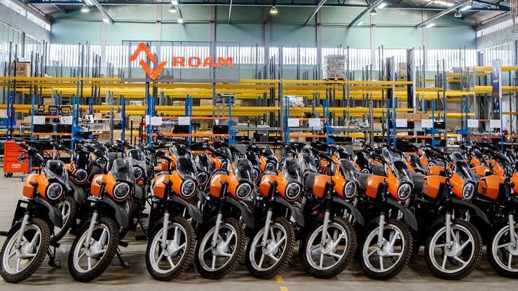 Rows of several motorcycles parked closely together in a dealership lot in Kenya, highlighting the scale of the motorcycle credit industry.