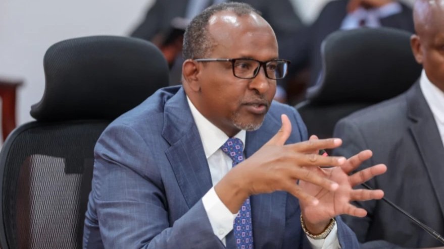 Close-up photo of Kenya Health Cabinet Secretary Aden Duale speaking at a microphone during an official government media briefing.