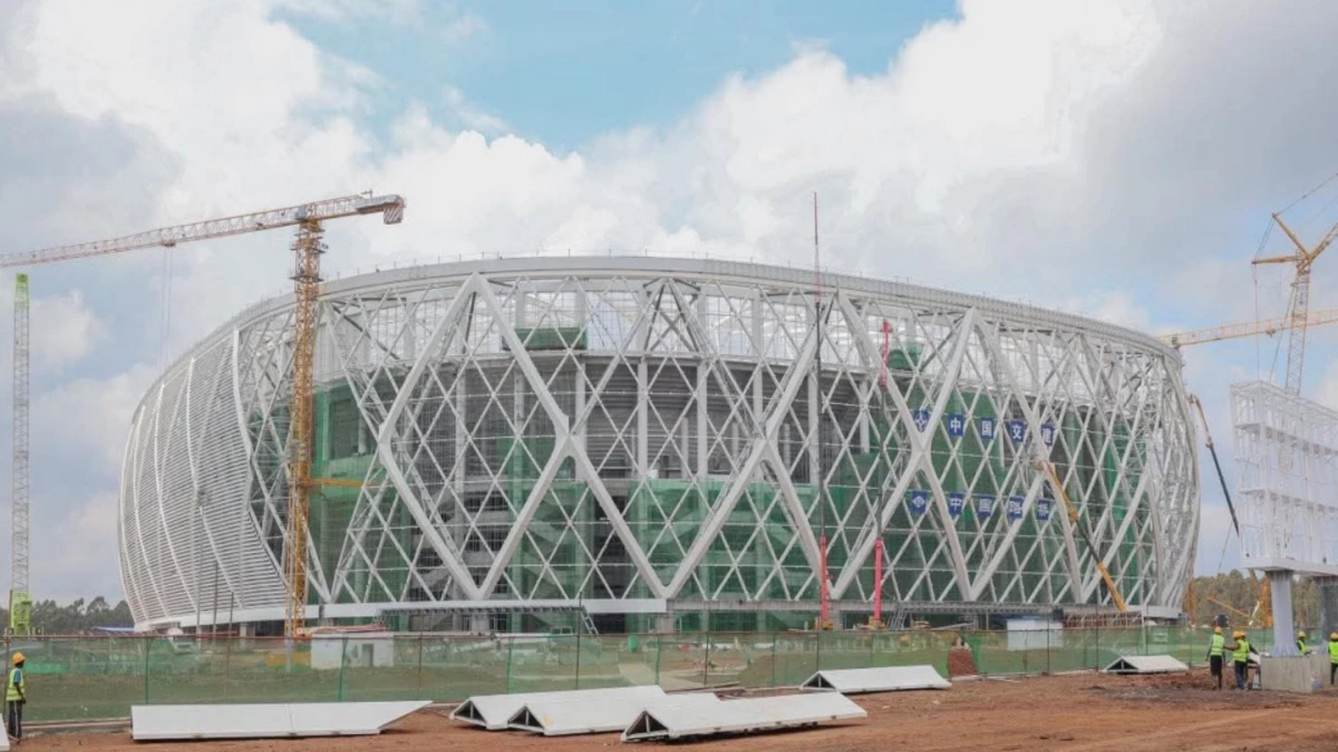 Aerial view of the Talanta Sports City Stadium construction site in Kenya, showing the partially completed stands and structure under a clear sky.