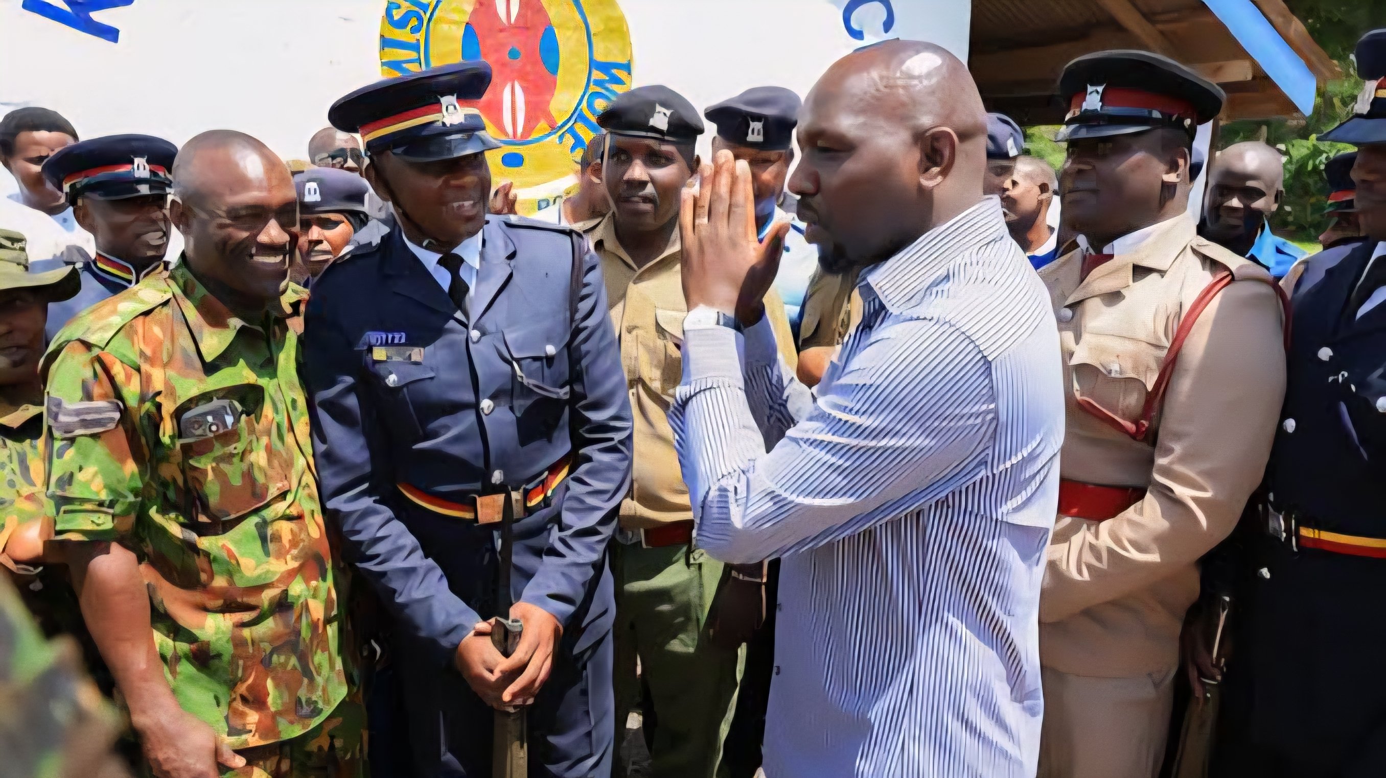 Featured Image Alt Text: A group of Kenyan police officers in various uniforms, including blue tactical gear and high-visibility vests, standing together during a public briefing.