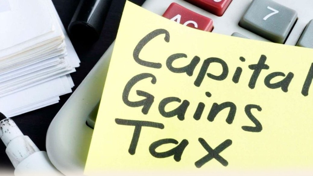 A yellow sticky note with the words Capital Gains Tax written on it placed on top of a desk calculator.
