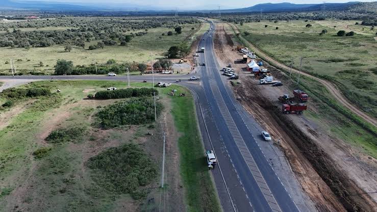 A wide view of a major highway construction site in Nairobi with heavy machinery and laborers visible against the city skyline.