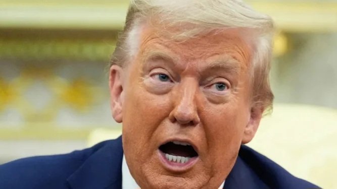 Close-up photo of Donald Trump speaking with an expressive, open-mouthed gesture during a formal briefing or press event.