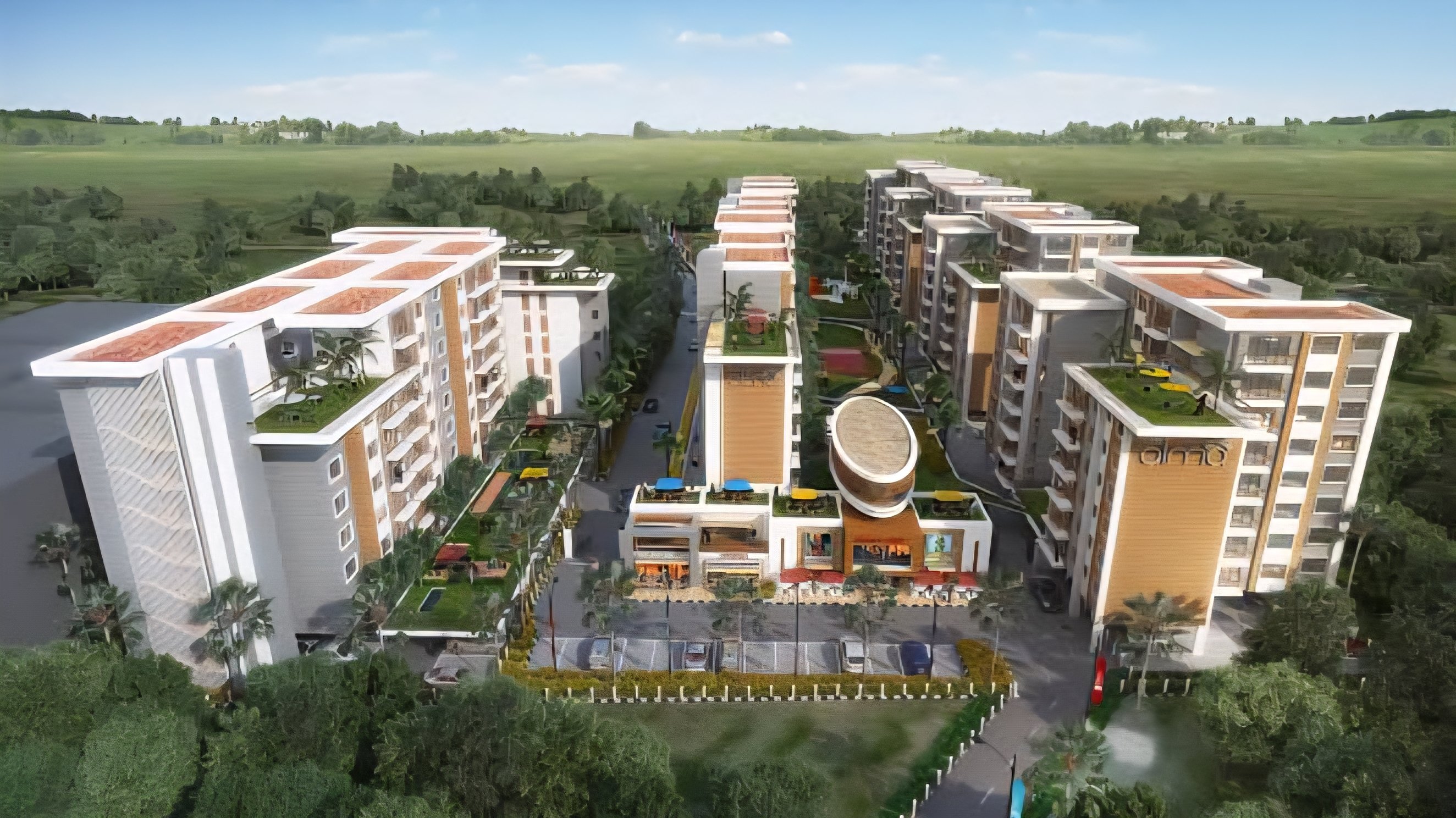 A wide-angle view of a multi-story residential apartment complex under construction with scaffolding and a crane visible against a clear sky.