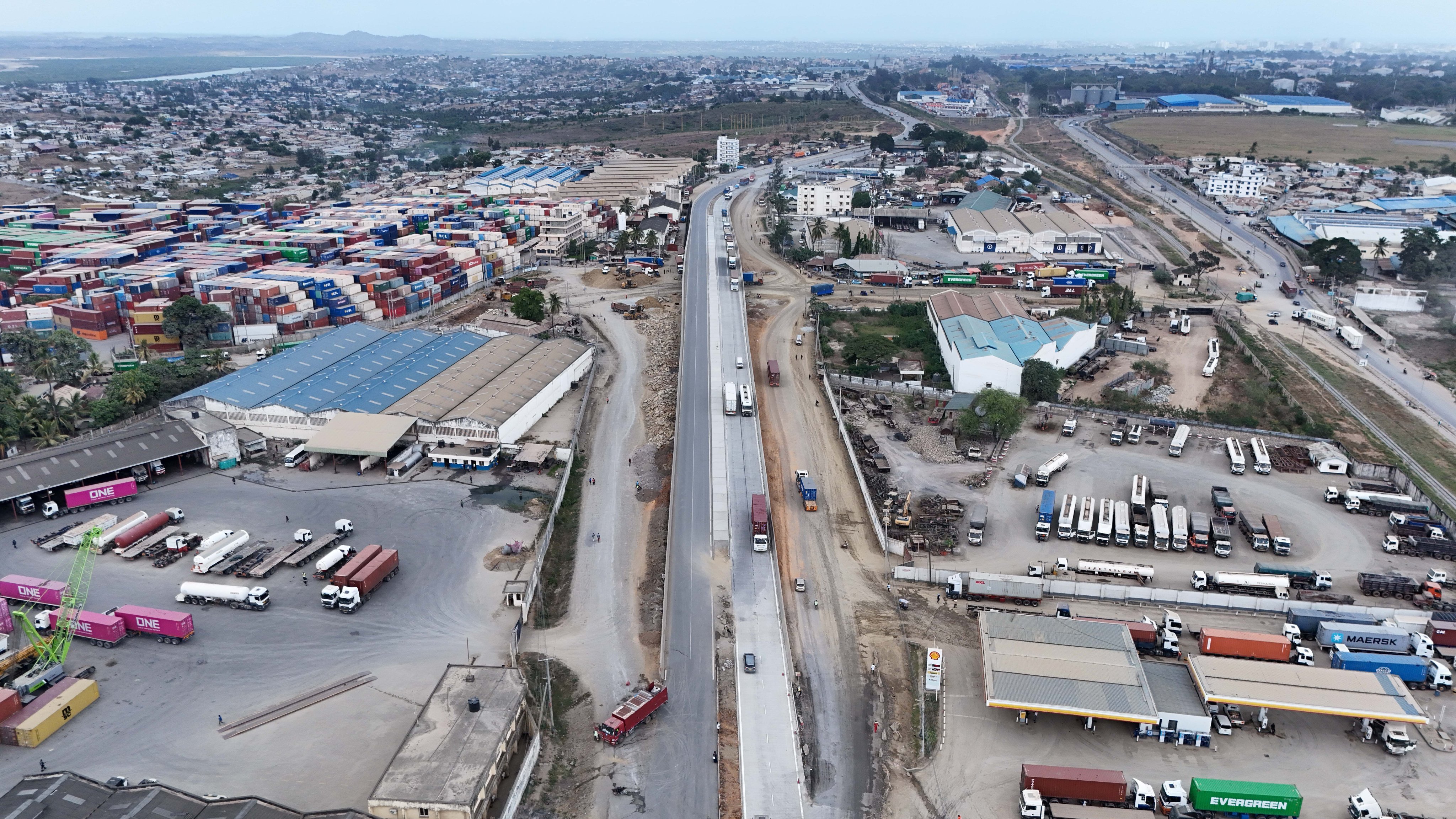 Aerial view of the ongoing Mombasa-Mariakani highway dualling project showing completed lanes, traffic, container yards, and construction zones near Mombasa port area.