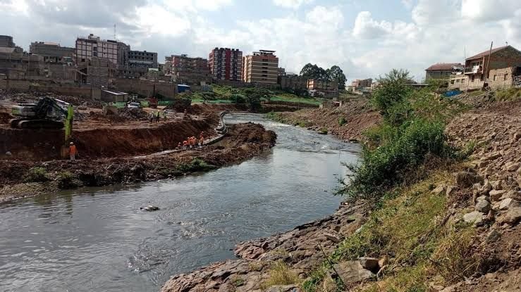 A wide shot of a section of the Nairobi River with informal settlements in the background.