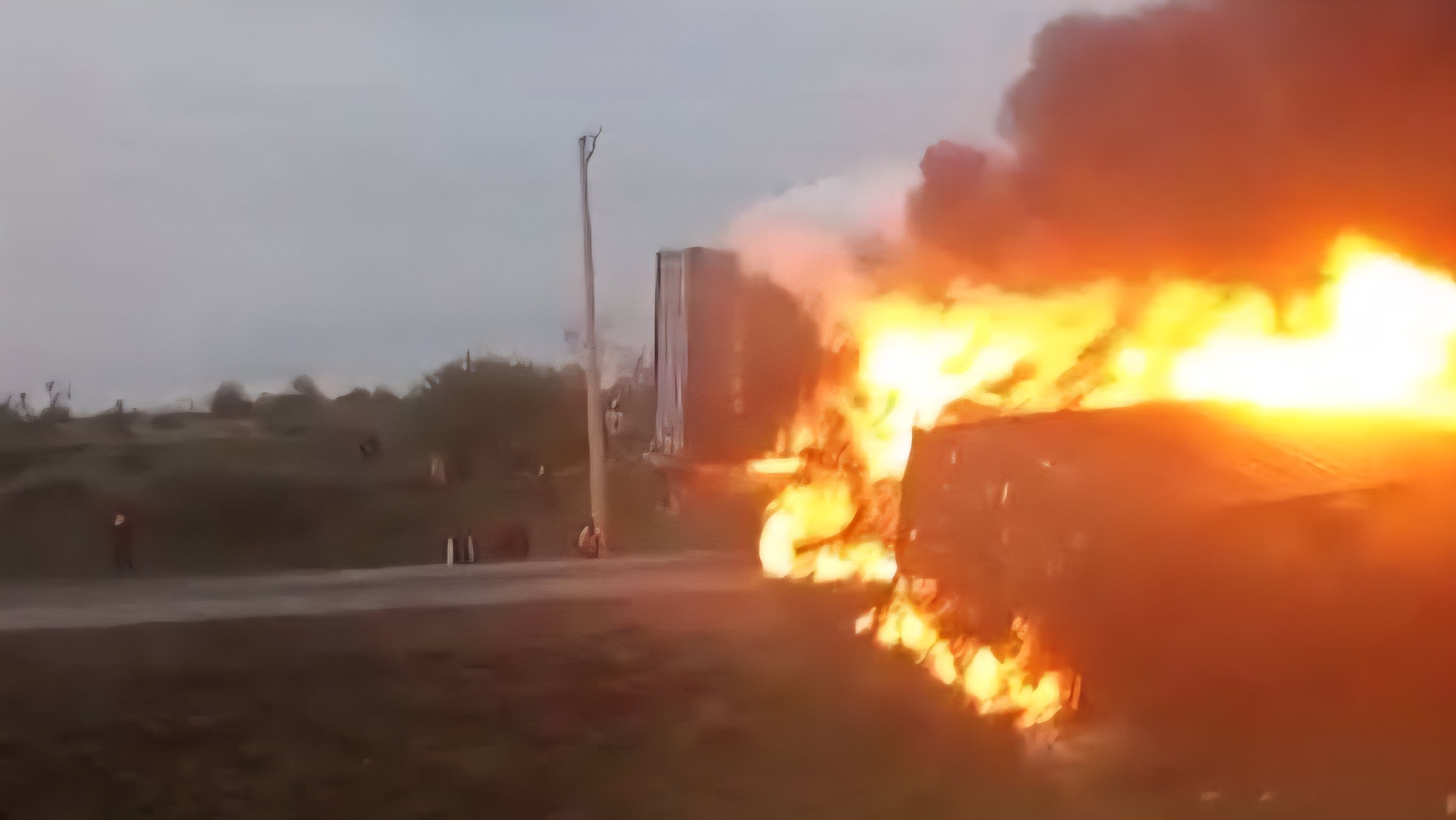 Two overturned commercial trailers on a highway with visible fire damage and emergency response teams at the scene near Athi River.
