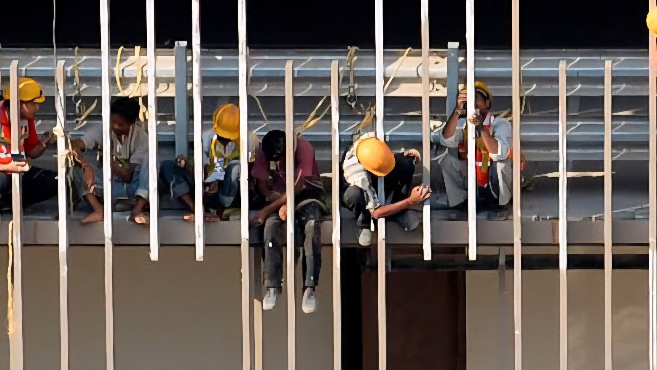 Construction workers in yellow hard hats working on a high-rise building frame in Kenya.