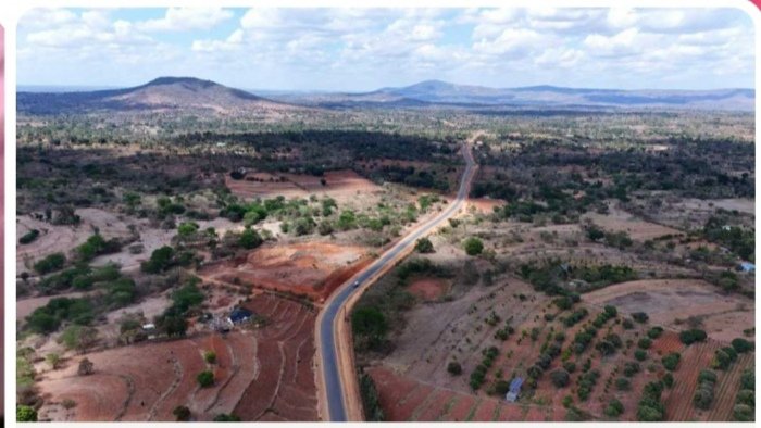 Heavy construction machinery paving the Tawa-Nguluni-Itangini Road with durable bitumen in a sunny, rural Makueni landscape, symbolizing infrastructure-driven economic transformation.