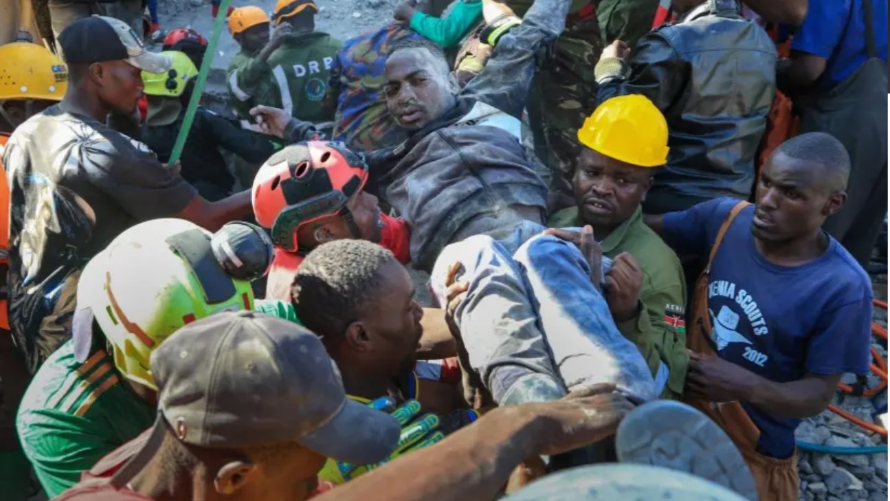 Rescue workers and volunteers in Nairobi's Shauri Moyo area carry an injured survivor away from the rubble of a collapsed multi-story building.